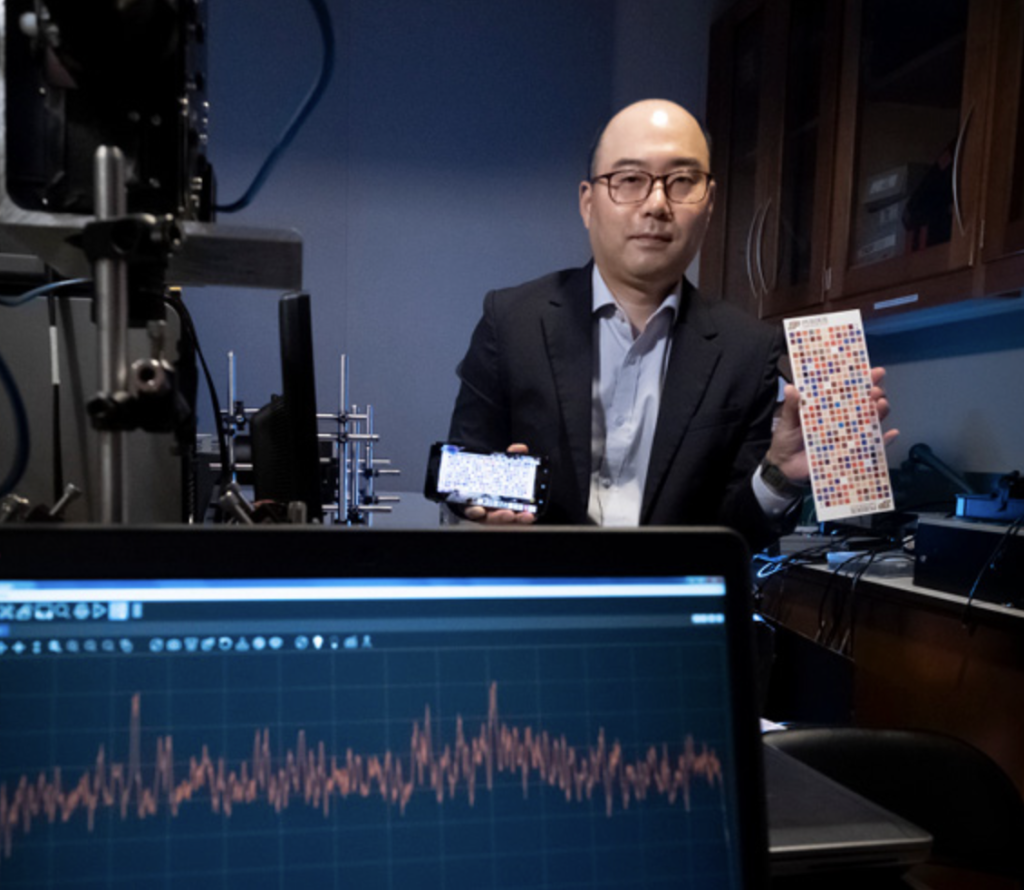 Purdue researcher Young Kim holding a smartphone and a color chart and looking into the camera.